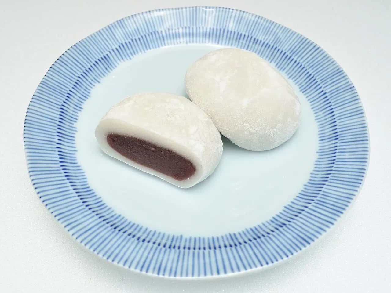 Japanese daifuku mochi with one piece cut open to show red bean filling