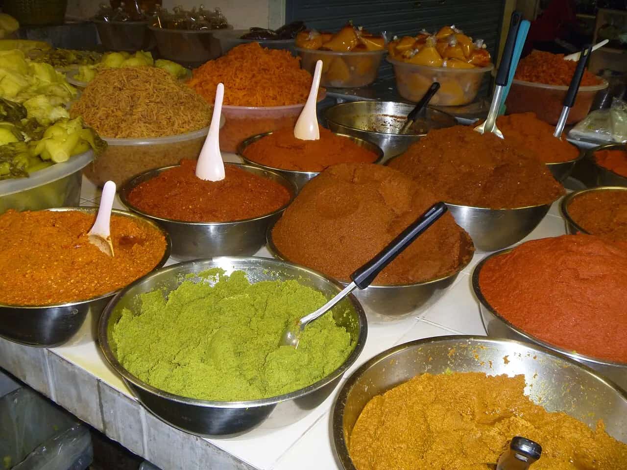 Bowls of red, green, yellow, and brown Thai curry pastes at a Phuket market