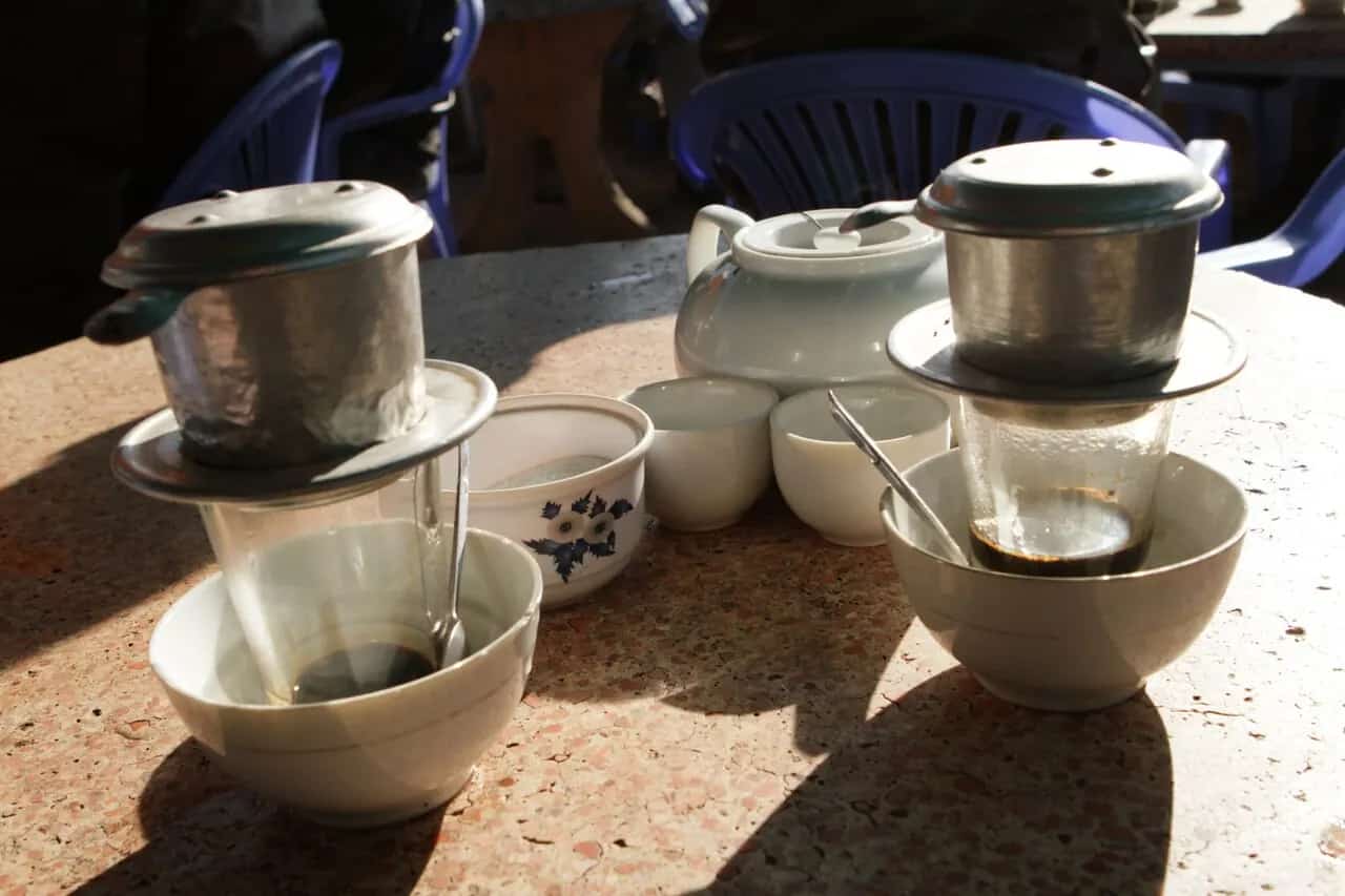 Vietnamese coffee dripping through metal phin filters in Da Lat